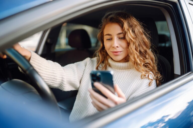 Portrait of woman texting on her smartphone while driving car. Car sharing, rental service, taxi app